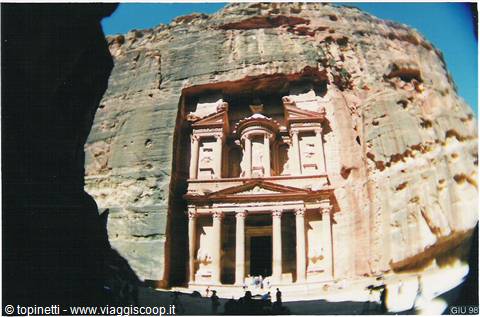 The Treasury carved in sandstone rock at Petra, tourists in shade