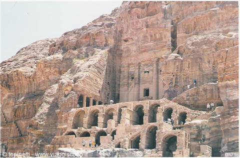 Tourists explore the Royal Tombs carved into the sandstone cliffs of Petra