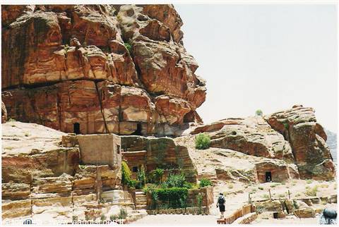 Rock-cut tombs carved in red sandstone at Petra, tourist walking in daylight