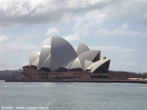White shells of Sydney Opera House across the water under cloudy sky