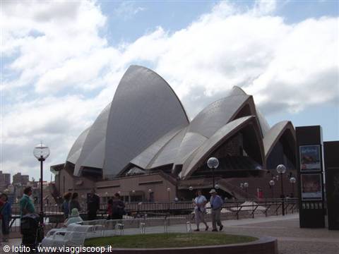 Tourists walk past the white sail shells of Sydney Opera House