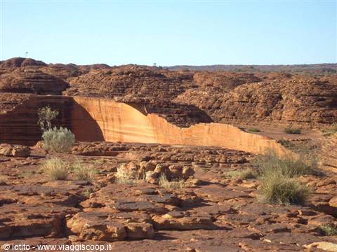 Red rock wall of Kings Canyon surrounded by spiky spinifex grass