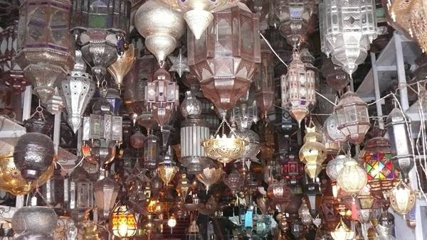 Ornate metal lanterns hanging from the ceiling of a lit souk