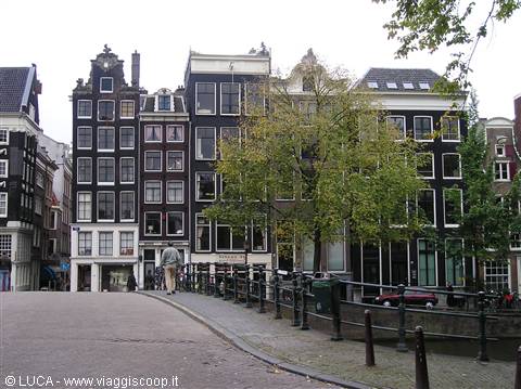 Amsterdam canal houses with gabled facades, a bridge and pedestrians