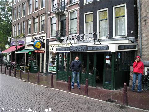 Tourist in front of the Rokerij coffeeshop along an Amsterdam canal