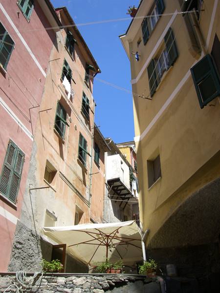 Colorful houses with green shutters and white umbrella in Riomaggiore, Cinque Terre