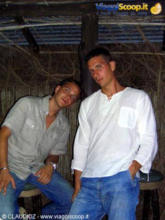 Two young men in jeans and white shirt sitting in a straw-walled bar