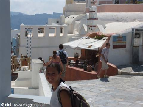 Smiling backpacker among whitewashed houses and umbrellas in Oia, Santorini