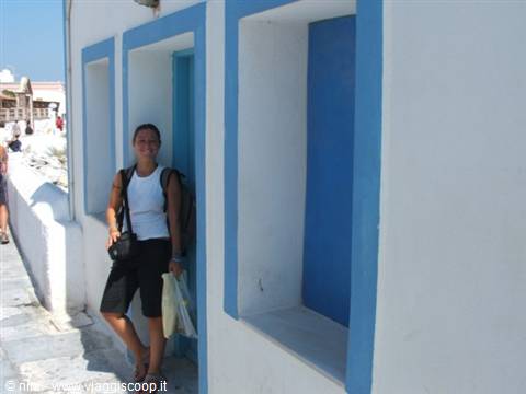 Woman with backpack next to blue door and window on white wall