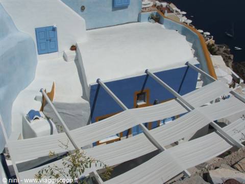 White roofs and blue walls in Oia, wooden pergola and sea in the background