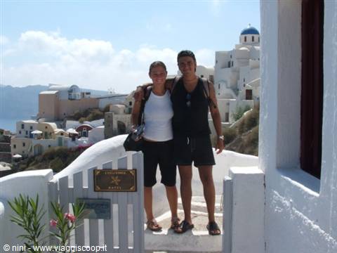 Smiling couple by white gate, blue-domed churches, Oia, Santorini