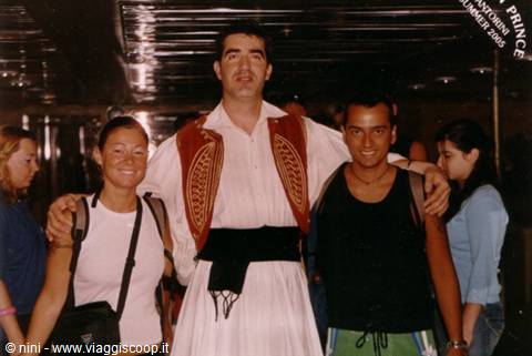 Tourist in traditional Greek costume with two young people aboard a ship