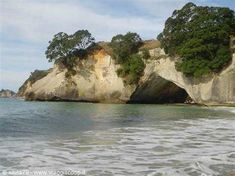 Cathedral Cove: limestone rock arch above the sand and foamy waves