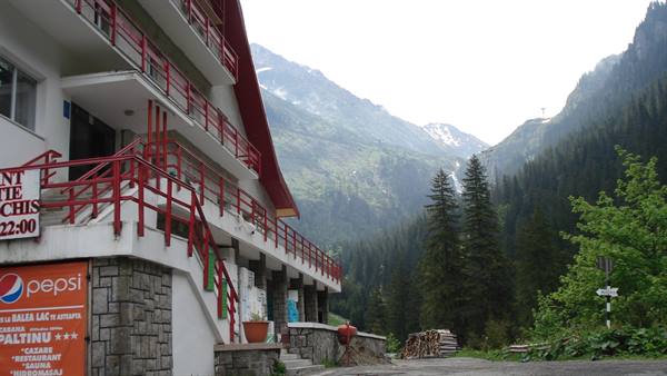 Hotel Paltinu with red balconies among mountains, waterfalls and dark firs