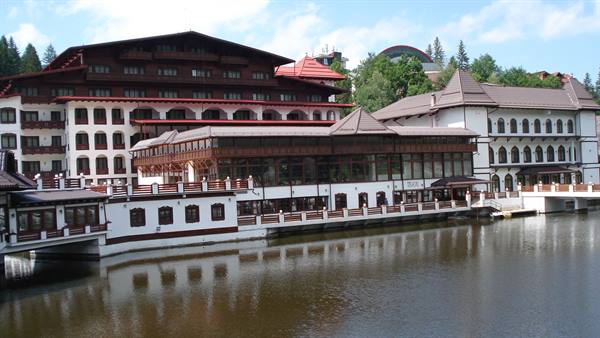 Wooden and white hotel complex reflected in the lake at Poiana Brașov