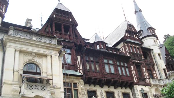 Carved wooden facade and white tower of Peleș Castle in Sinaia