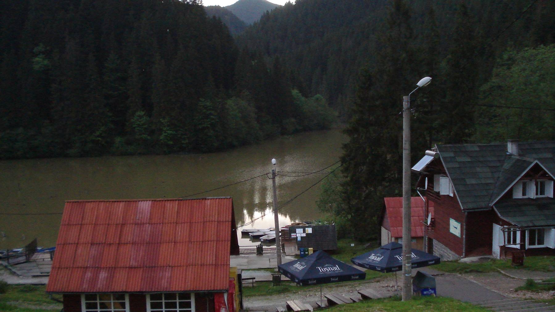 Red rooftops and umbrellas by Red Lake, dark forest and dusk light