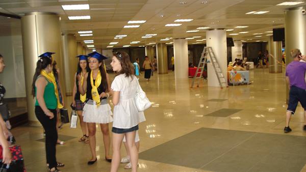 Girls in graduation caps and stoles chatting in a bright hall