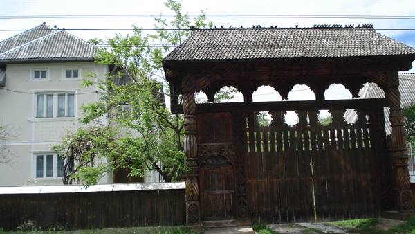 Carved wooden gate in front of a rural house, daylight