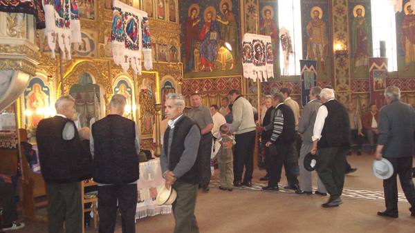 Men queuing inside an Orthodox church with golden frescoes and icons
