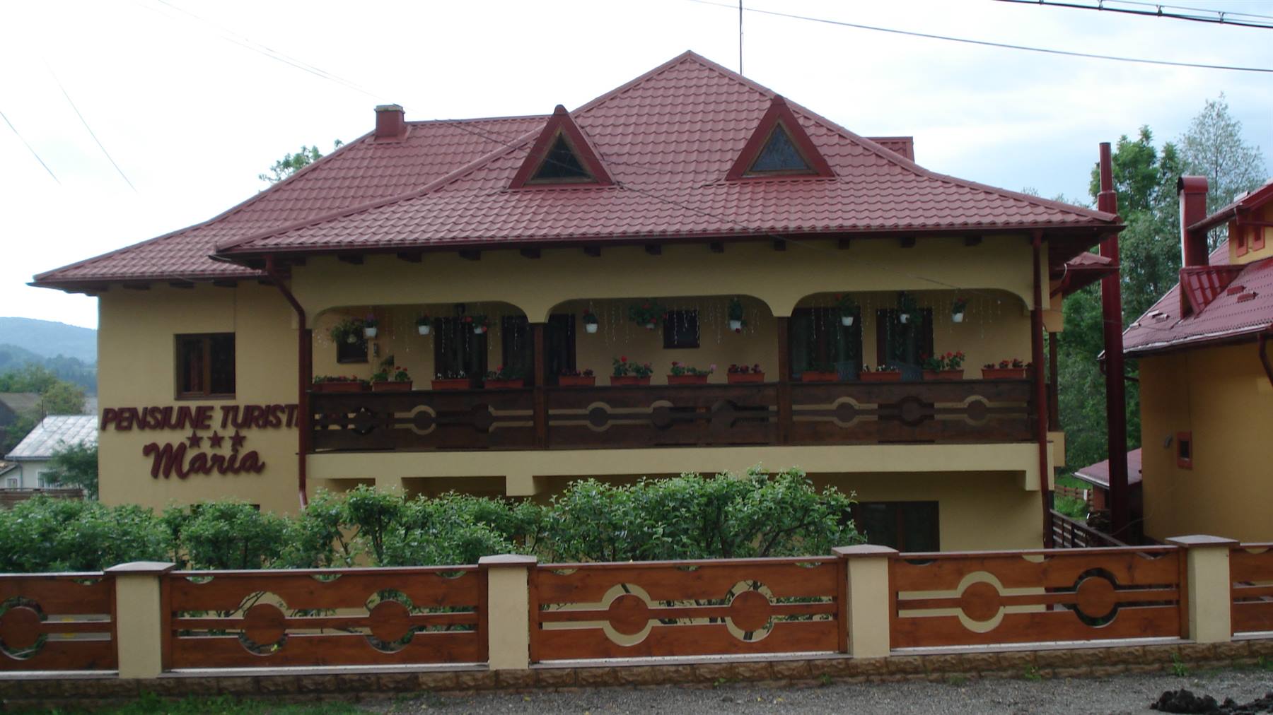 Pension Maria guesthouse, yellow building with red roof and wooden fence