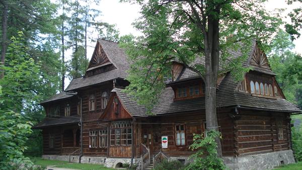 Wooden villa in Zakopane style, shingled roof, surrounded by tall trees