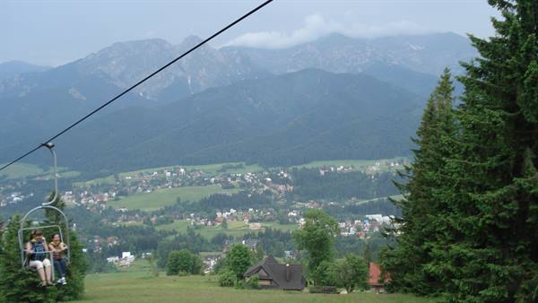 Chairlift seats above a green valley, Tatra mountains shrouded in clouds