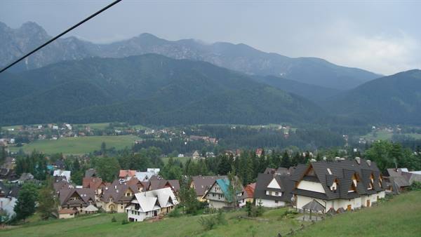 Village of sloped-roof houses at the foot of cloud-covered Tatra mountains