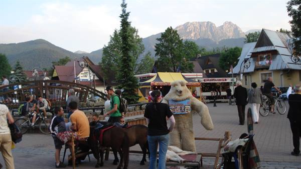 Pony rides and a bear mascot on Krupówki street, Giewont peak behind, Zakopane