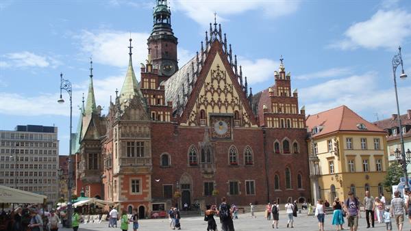 Tourists strolling in front of the brick Gothic Town Hall on Wrocław's Rynek