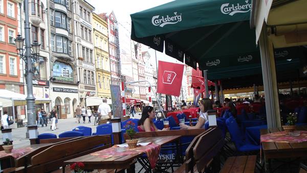 People sitting at outdoor café tables, colorful buildings in the background
