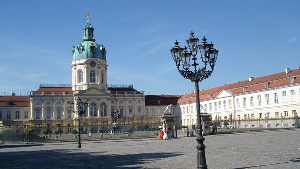 Charlottenburg Palace, Berlin: baroque facade, wrought-iron lanterns and tourists under blue sky