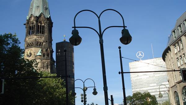 Berlin's Kaiser Wilhelm Memorial Church among street lamps and buildings under blue sky