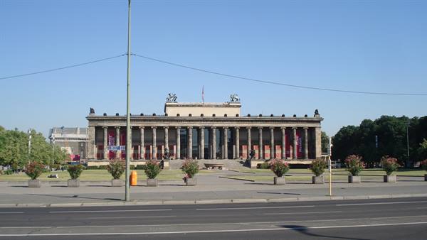 The Altes Museum in Berlin, columned facade under blue sky, empty streets in foreground
