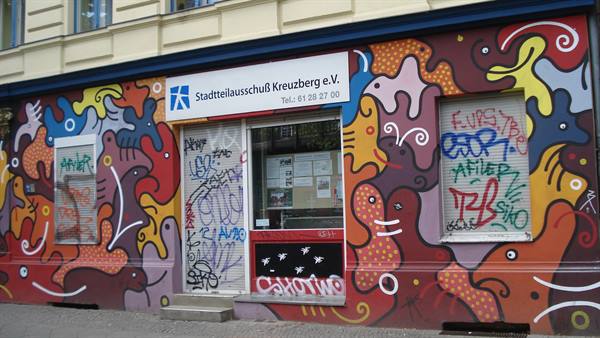 Stadtteileauschuss Kreuzberg entrance with colorful painted mural shapes and graffiti