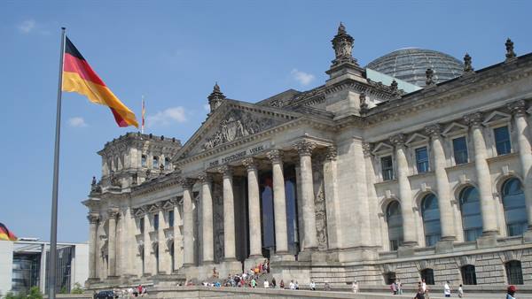 German flag waving in front of the Reichstag in Berlin, tourists on the steps