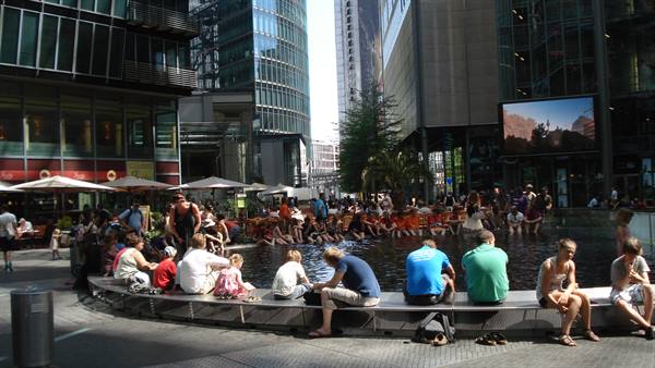 People sitting around a fountain beneath the glass towers of Sony Center