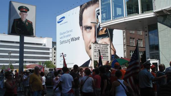Crowd and American flags at the Checkpoint Charlie sign in Berlin