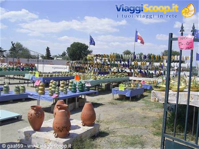 Open-air market with terracotta pots and pottery on tables, French flags