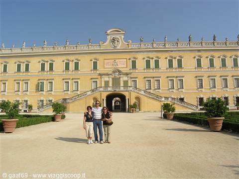 Three tourists pose in front of a yellow ducal palace facade with statues