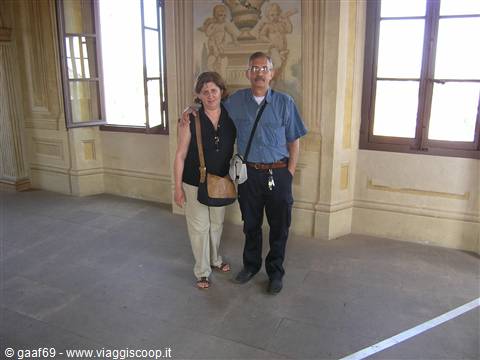 Couple standing in a frescoed palace hall, daylight from windows
