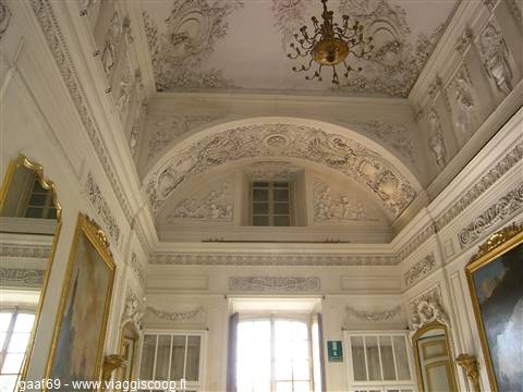 White stucco ceiling and golden chandelier inside a baroque hall