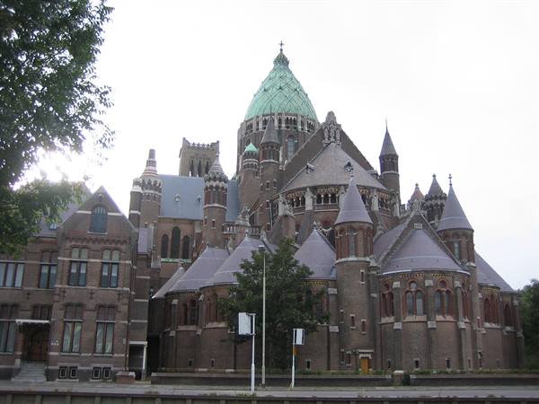 Saint Bavo Cathedral in Haarlem, brick towers and green dome under cloudy sky