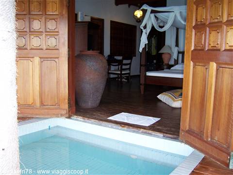 Private plunge pool before wooden doors, bedroom with canopy bed and terracotta vase