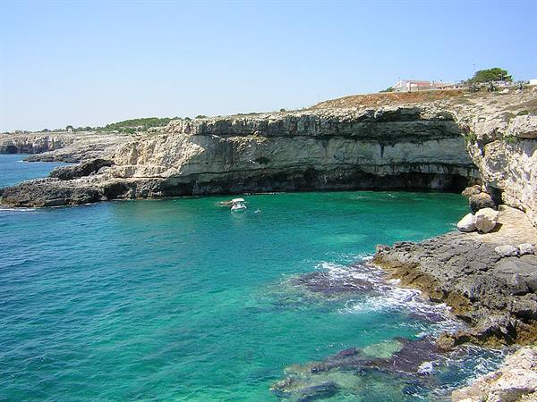 Limestone cliffs over turquoise water, a small boat anchored in the cove