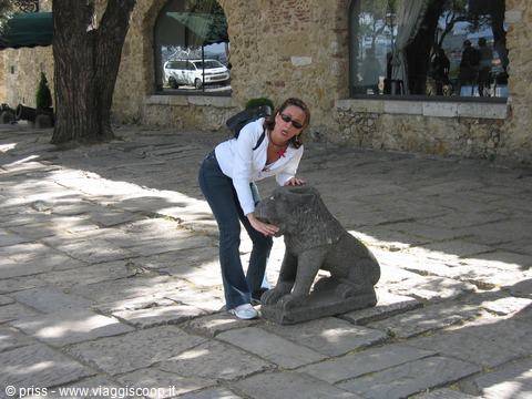 Woman petting a stone lion statue on the cobblestones