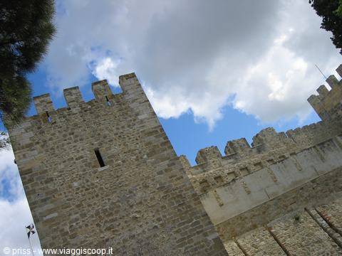 Crenellated stone tower of São Jorge Castle against white clouds