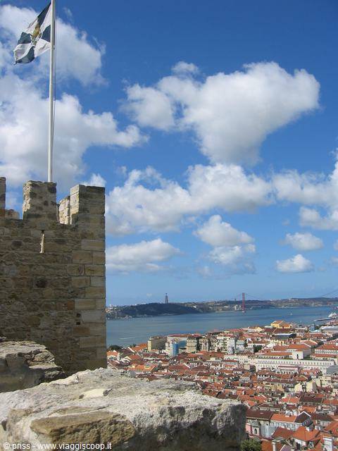 Stone battlement tower with flag, Lisbon rooftops and 25 de Abril bridge