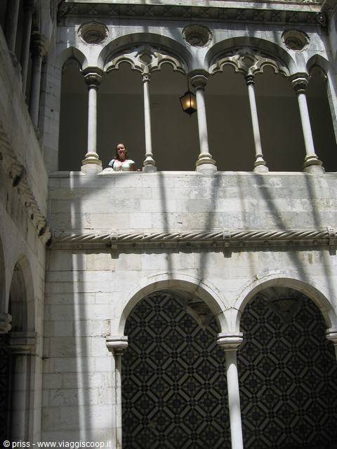 Tourist on the stone cloister of the Jerónimos Monastery, shadows and gothic arches