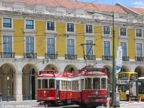 Red tourist trams in front of yellow arcaded buildings at Praça do Comércio, Lisbon